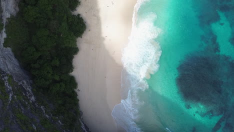 drone shot top view of waves breaking on a white sand beach in bali