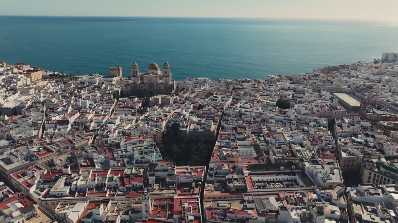 Luftfoto med drone af Cádiz i Spanien, Andalusien, Europa på en lys og solrig dag med udsigt til Cádiz-katedralen og havnefronten. Filmisk optagelse, der flyver baglæns. Mørk filmisk farvejustering
