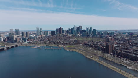 Aerial-panoramic-ascending-footage-of-city-with-downtown-skyscrapers.-Fly-above-wide-River-Charles.-Boston,-USA