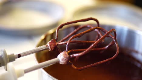 deliciosa masa de pastel de chocolate vegano goteando de la mezcladora eléctrica en un cuenco de mezcla mientras se hornea el postre en la cocina desliza a la izquierda