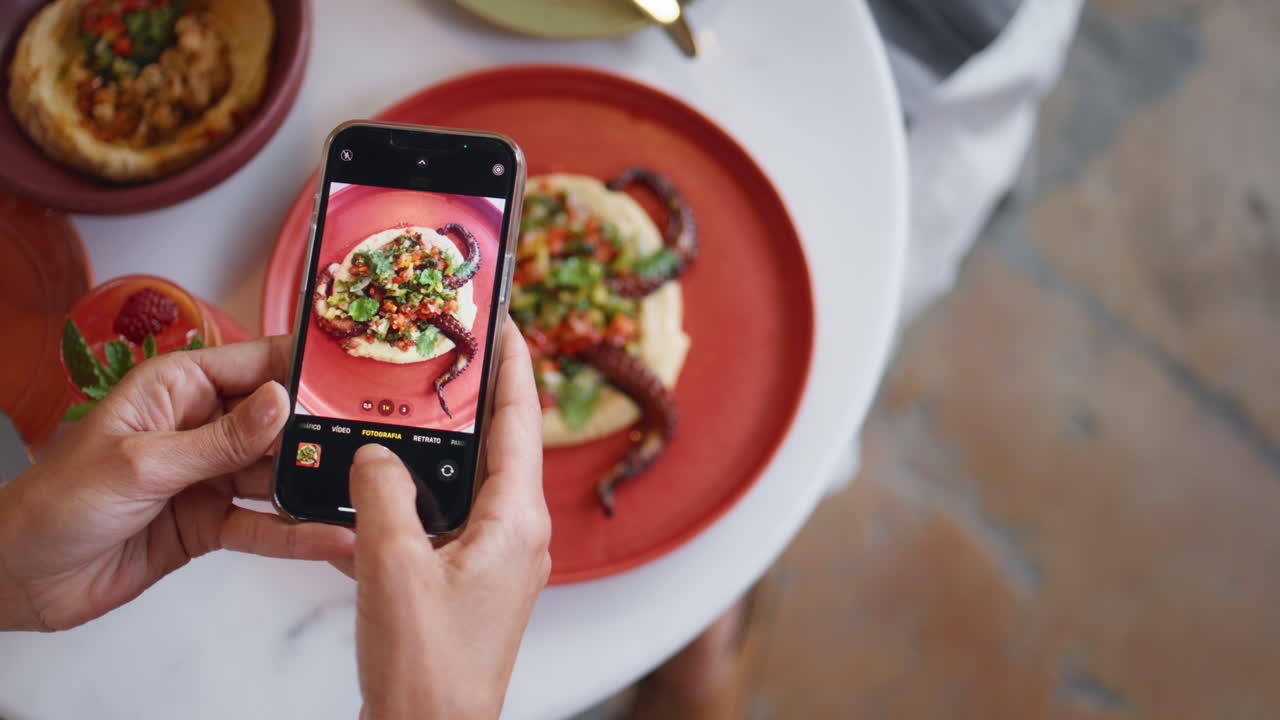 레스토랑 테이블 에서 휴대 전화 를 사용 하여 맛있는 저녁 식사 의 사진 을 찍는 여자 의 손