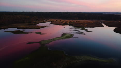 Cielo-Rojo-Vívido-Que-Se-Refleja-En-El-Agua-Tranquila-Del-Lago,-Vista-Aérea-De-Drones