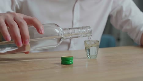 person pouring alcohol into a shot glass