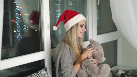 Woman with teddy bear. Happy woman with teddy bear sitting on window sill celebrating New Year