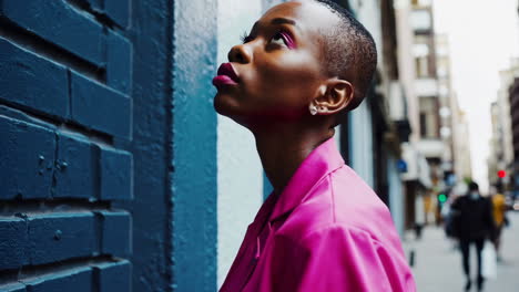 stylish woman in a pink blazer by a blue wall in the city