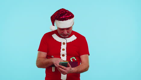 Mann-Im-Modischen-Weihnachts-T-Shirt-Schaut-Auf-Das-Smartphone-Display-Und-Freut-Sich-Aufrichtig-über-Den-Sieg,-Den-Erfolg-Und-Das-Glück