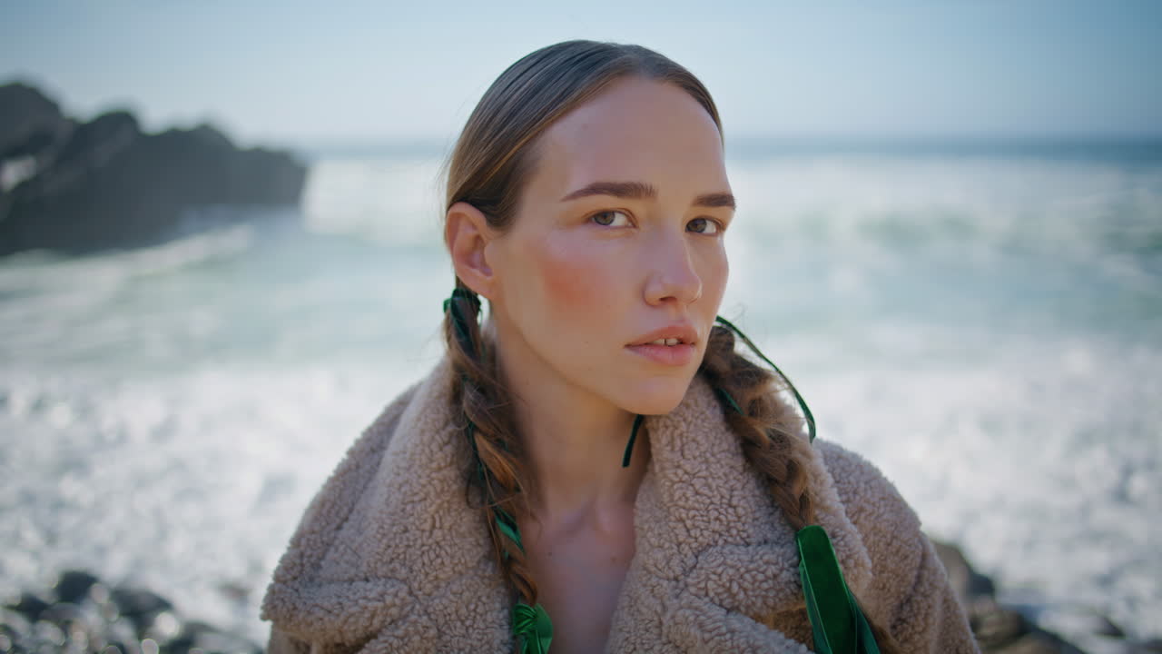 девушка на берегу моря смотрит в камеру на пенящийся океан портрет. созерцательная спокойная модель