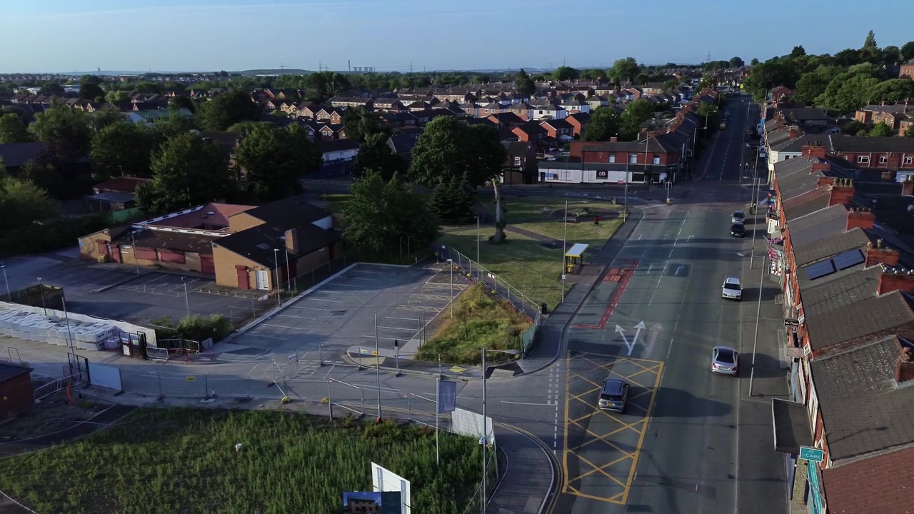 Vista aerea su una tranquilla strada di una città britannica all'alba, con un ambulatorio medico e una fila di negozi