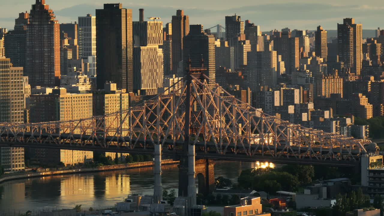 Aerial view of the Queensboro Bridge at sunrise. Shot along the East River with Roosevelt Island and Manhattan in the background