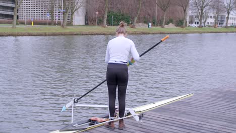 female rower preparing to go out on utrecht canal for training in a single scull boat