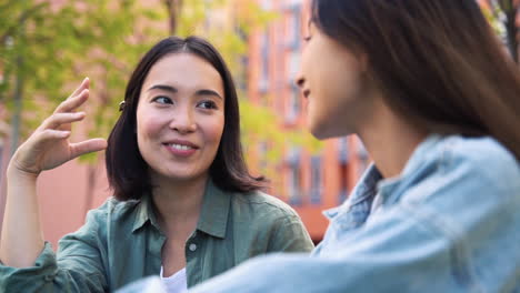bastante joven mujer japonesa sentada y hablando con su amiga al aire libre