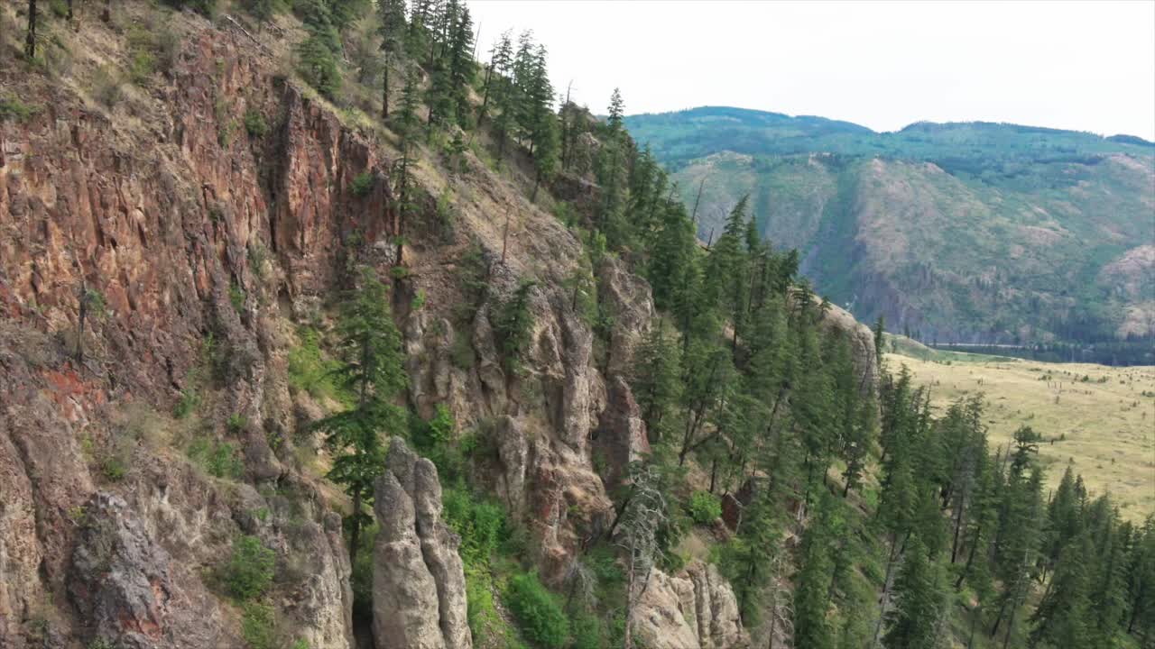 эффектный снимок с подхода к скалистым утесам красного цвета, окруженным соснами, в долине реки южный томпсон недалеко от камлупса, штат канада