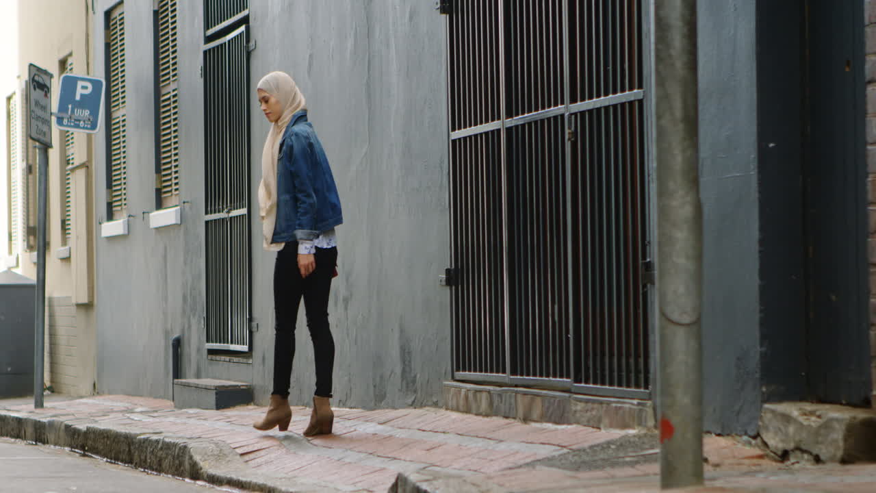 히자브를 입은 여성이 거리에서 고 있습니다.