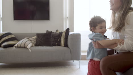 cheerful toddler standing in living room, pointing up.