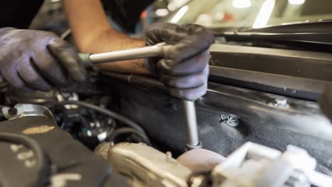 Car-mechanic-working-with-wrench-under-bonet-on-car-close-up-shot