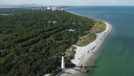 Tourists-relax-and-enjoy-beautiful-sunny-day-at-beach-by-cape-florida-lighthouse,-atlantic-ocean