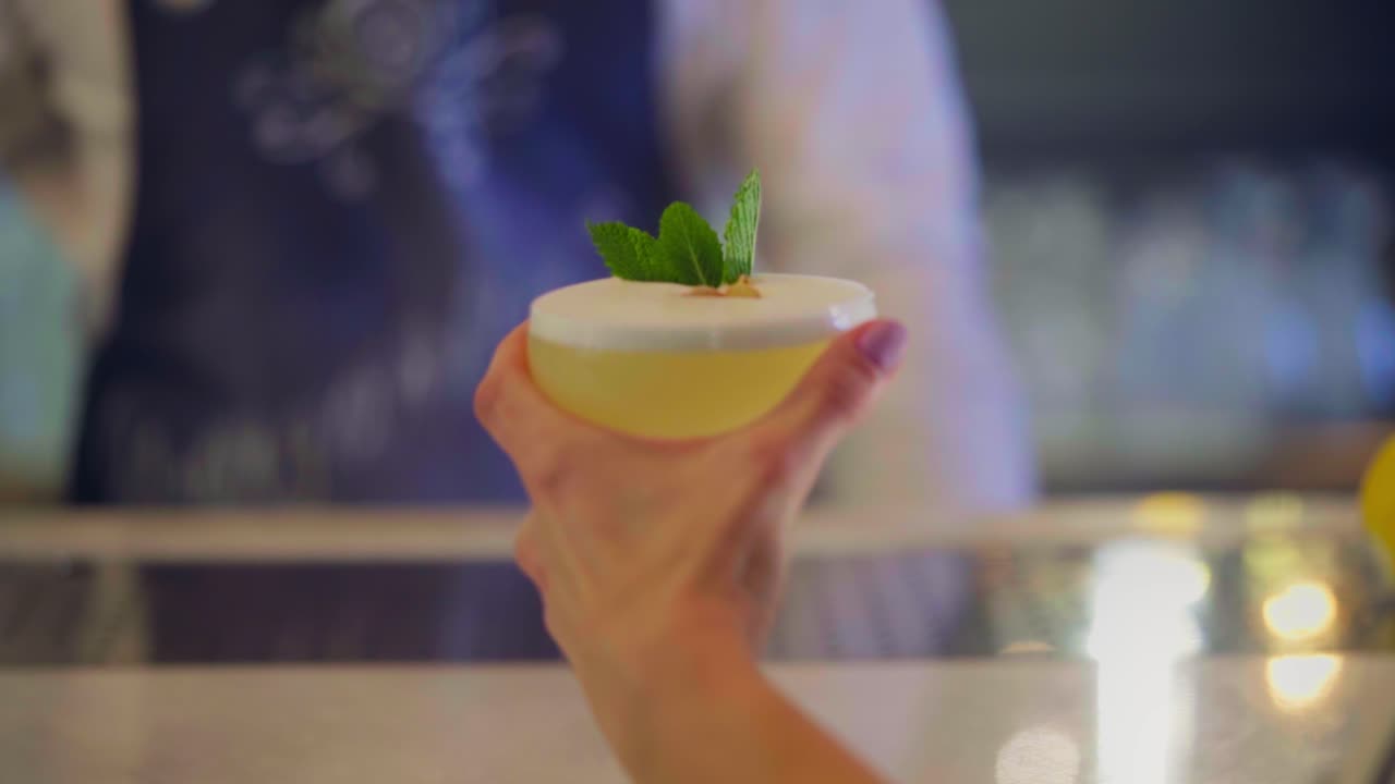 mujer bebe un cóctel con menta en un mostrador de bar