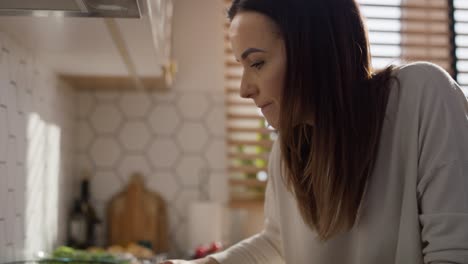 Caucasian-middle-aged-woman-tasting-a-soup-and-adding-some-spices