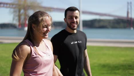 Happy-sporty-young-couple-embracing-and-talking-during-stroll.