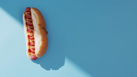 video de un perrito caliente con mostaza y ketchup en una superficie azul