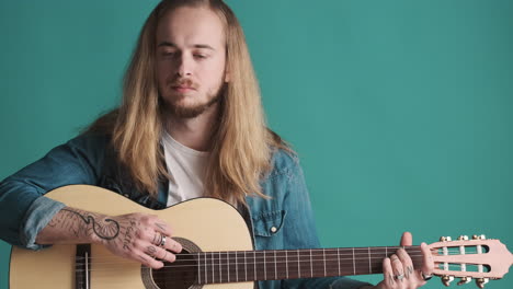 caucasian young man playing guitar on camera.