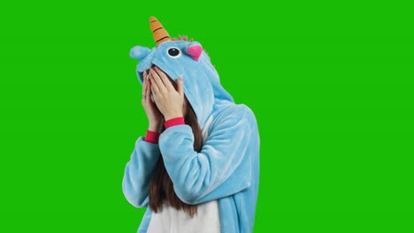 portrait of a cute young brunette girl in a beautiful unicorn costume on chrome key green background. smiling and playing. animator in costume. unicorn pajamas. 4k video with alpha channel