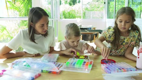 mother and daughters beading together