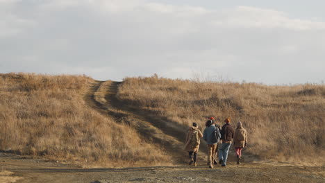 visão de medo de um grupo de amigos adolescentes conversando e caminhando em um caminho de campo de trigo em um dia ventoso