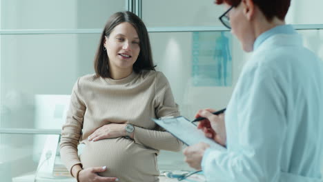 pregnant woman talking to doctor on consultation in clinic