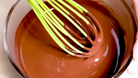 whisk stirring melted chocolate in a glass bowl