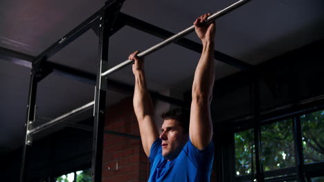 Man doing chin up exercises on a pull up bar in a gym