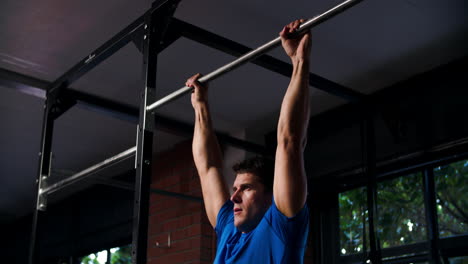 man doing chin up exercises on a pull up bar in a gym