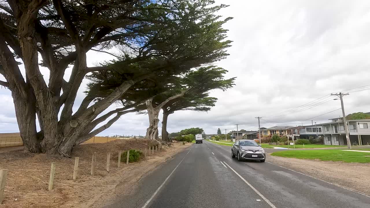 A serene drive on Great Ocean Road with coastal views, lush greenery, and overcast skies, capturing the essence of Australian landscapes