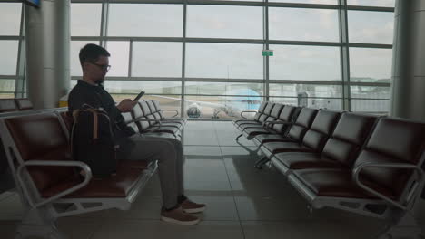 hombre esperando un vuelo en la terminal del aeropuerto