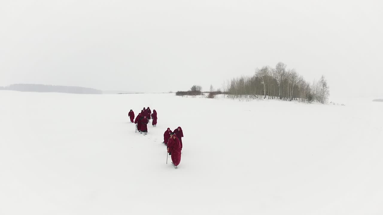 겨울 에 얼어붙은 호수 를 가로질러 고 있는 승려 들