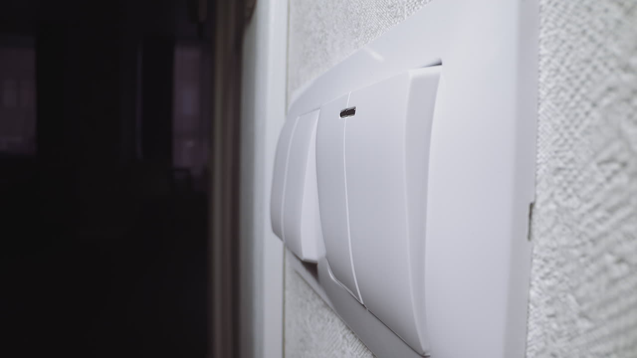 mujer apaga la luz tocando el interruptor instalado en la pared