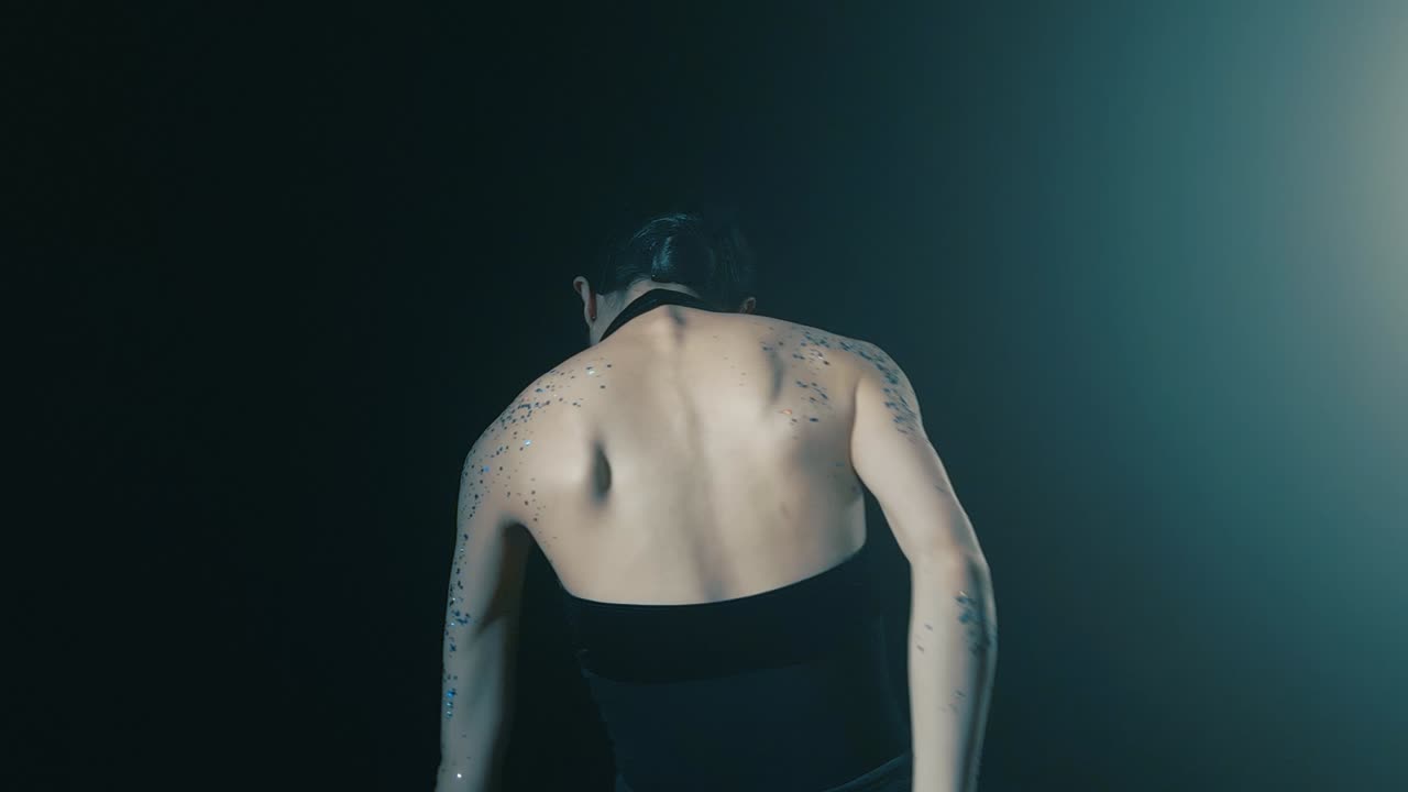 어두운 무대에서 발레를 춤추는 허리에 은 여자