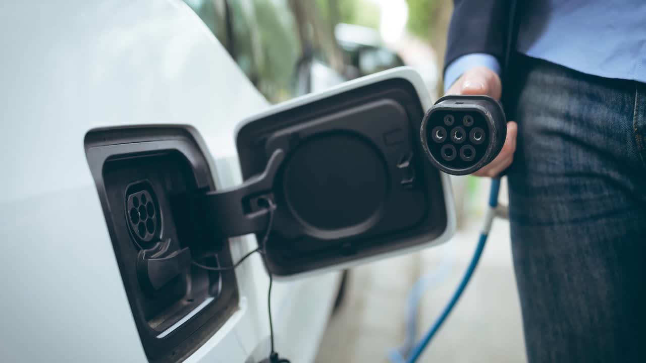 Elektrikli arabayı şarj eden beyaz kadının orta bölümü.