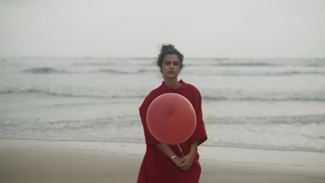 an elegant indian woman, adorned in a captivating red ensemble, stands on the beach