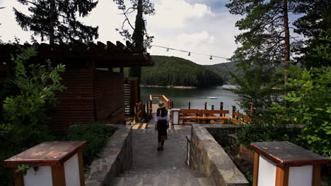 chica rumana caminando por el puente panorámico del lago - vista trasera
