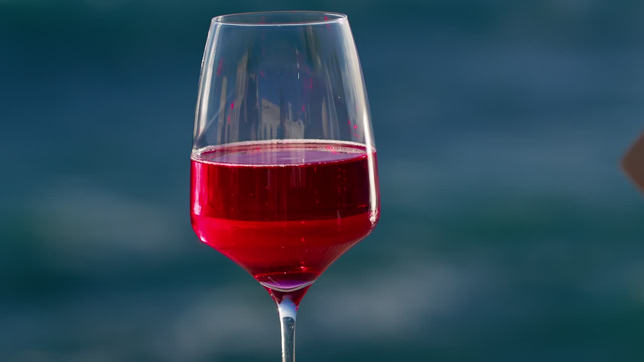 이탈리아 시칠리아의 바다에서 바람이 불면서 책 페이지를 뒤집는 소녀와 함께 와인 한 잔의 클로즈업