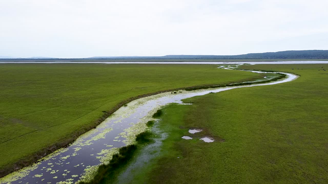 La vasta pianura umida aperta di Ira Lalaro, paesaggio di lago, ruscello e fiume nel distretto di Lautem all'interno del Parco Nazionale Nino Konis Santana, Timor Est; volo di drone aereo su un habitat esteso.