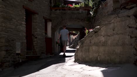 man in shorts and a t-shirt walking through a typical old italian alp village