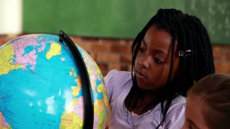 Cute-pupils-looking-at-the-globe-in-classroom