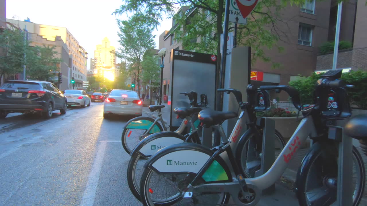 Editorial, bike share station, Montreal canada, street view, camera moving forwards, cars and people passing, sunset moment.