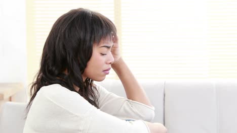 Stressed-woman-holding-her-head-on-couch-