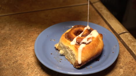 cinnamon bread topped with icing dripping in slow motion - closeup shot