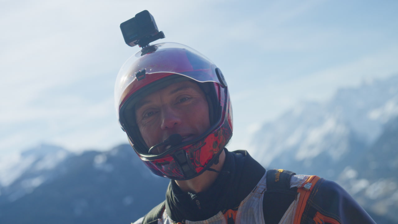Wingsuit BASE jumper flying over Verbier surrounded by alpine mountains with snow-covered peaks. High-speed flight, dramatic scenery, and cinematic extreme sports action in the Swiss Alps.