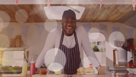 animation of spots of light floating over smiling african american fast food seller