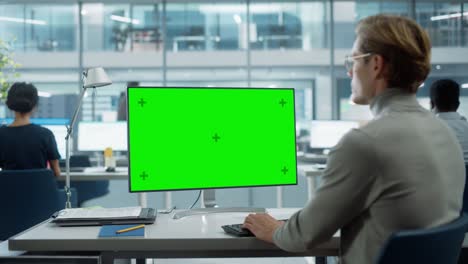cerca por encima del hombro de un hombre de negocios trabajando en una computadora de escritorio con pantalla verde con tecla de croma. gerente de proyectos digitales escribiendo datos, usando teclado y ratón.
